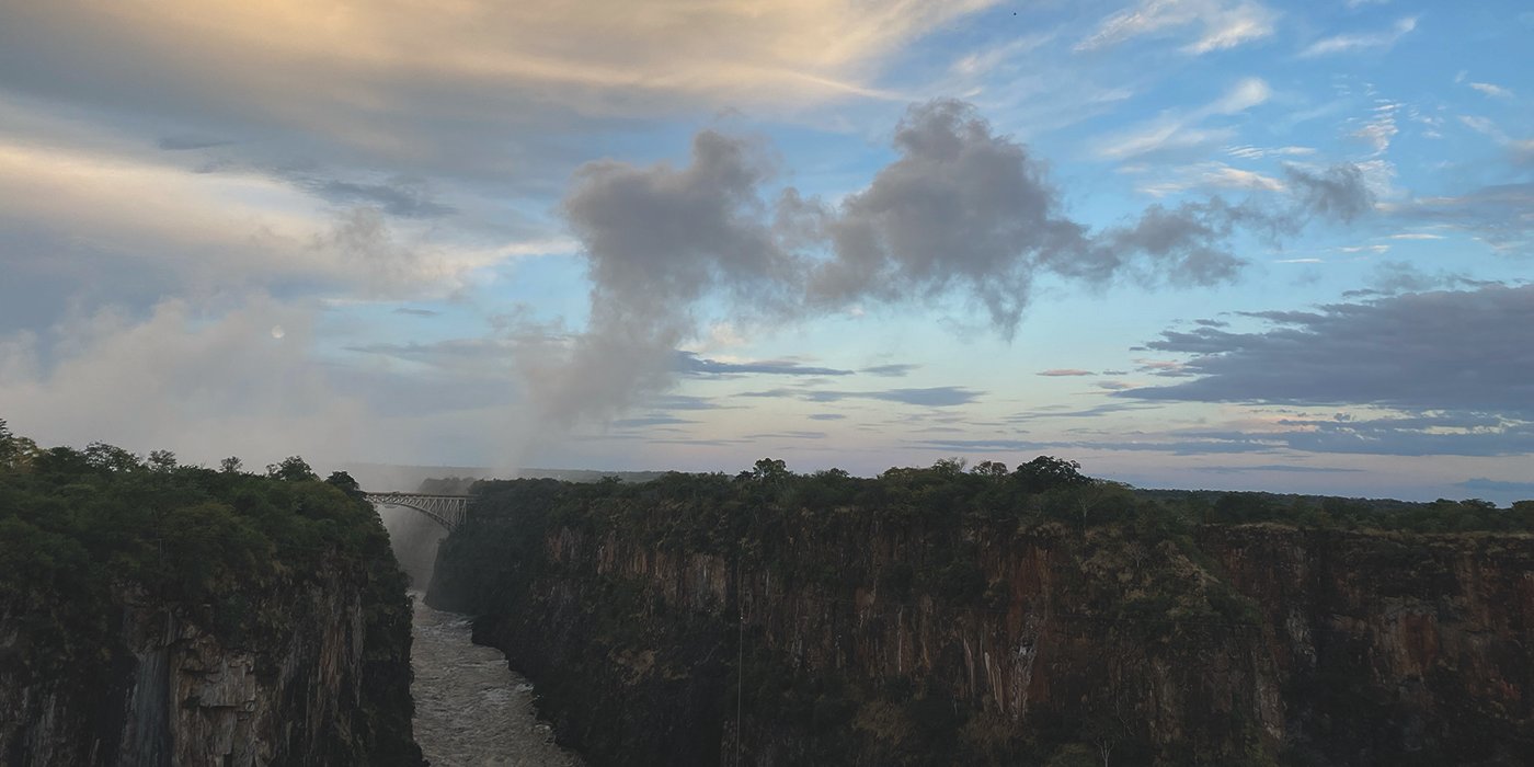Victoria Falls, between Zambia and Zimbabwe, is a stunning sight at dawn. The rising sun bathes the rocky edge in golden light as the Zambezi River flows gracefully over, creating rainbows in the mist. It's a powerful and beautiful testament to nature's majesty.