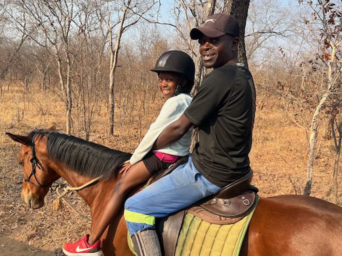 A father and daughter share a memorable moment on horseback amidst the untamed African bush.
