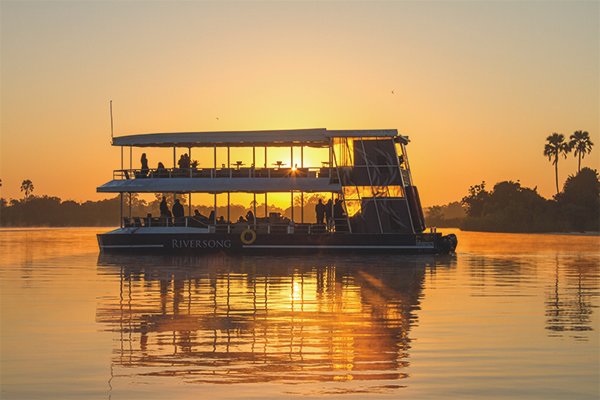 Embark on a mesmerizing river cruise along the enchanting Victoria Falls at sunset. As the golden hues of dusk paint the sky, witness the majestic cascade of water against the backdrop of the African horizon. The scene unfolds in unparalleled beauty, a symphony of colors and tranquility merging to create an unforgettable experience of nature's splendor.