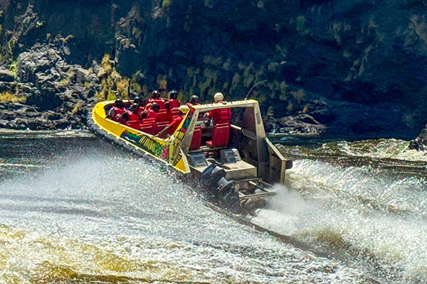 jet-boat-zambezi-river-victoria-falls-zimbabwe-adventure High-speed jet boat adventure on Zambezi River near Victoria Falls Zimbabwe showcasing adrenaline water sports and adventure activities in dramatic gorge